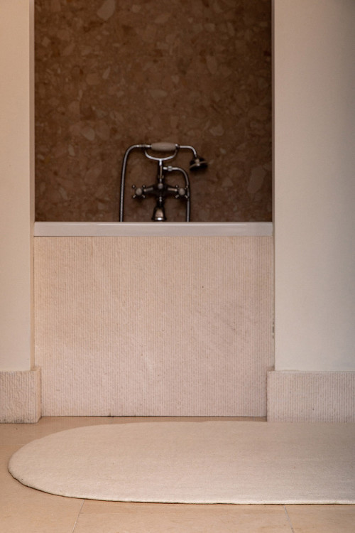 A beige oval felt rug for the bathroom