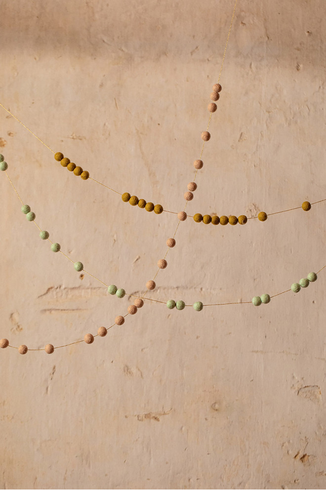 Felt pompons on a golden thread to create a playful garland