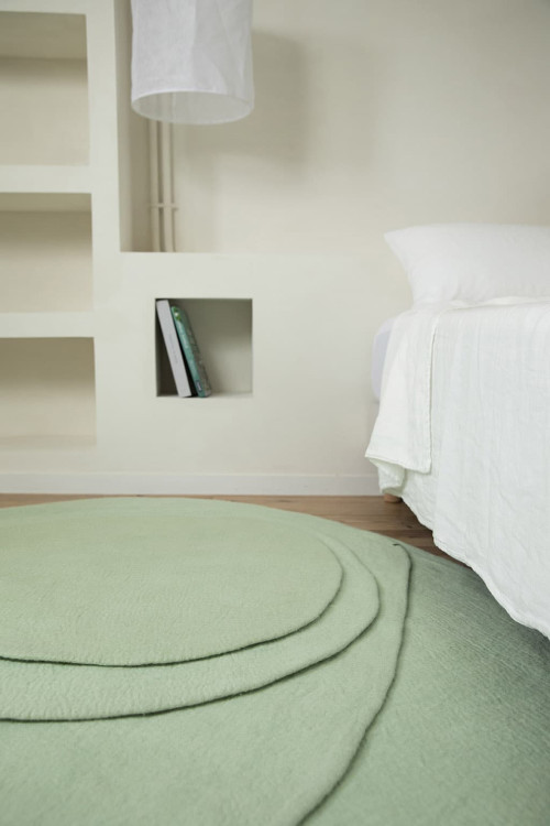 Ein organischer Teppich aus gefilzter Wolle am Fußende des Bettes
