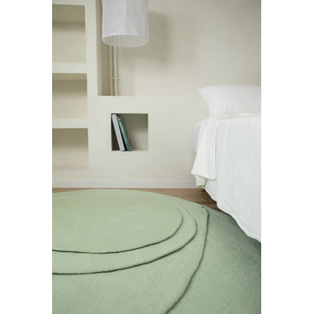An organic felted wool rug at the foot of the bed