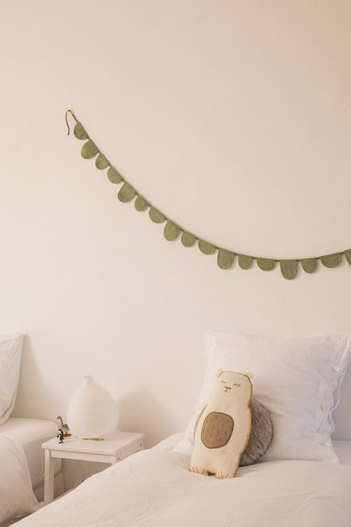 Un coussin grizzly et une guirlande pour décorer une chambre d'enfant