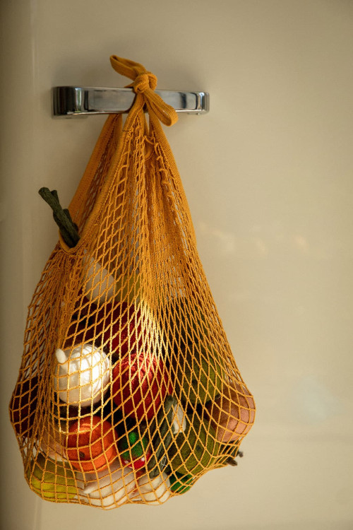 a net bag filled with handmade felted wool fruits and vegetables