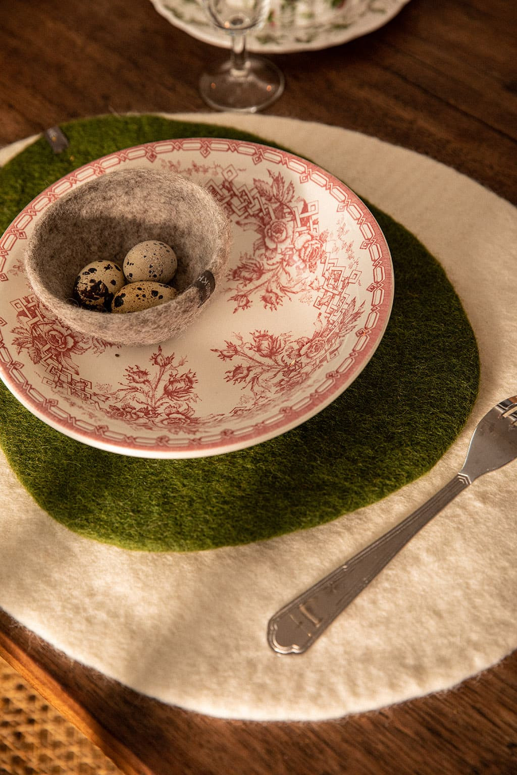Un petit sous de plat vert foncé sur un set de table écru pour rehausser la vaisselle