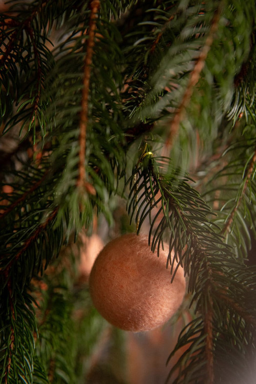 Une boule de Noël feutrée faite à la main dans le sapin