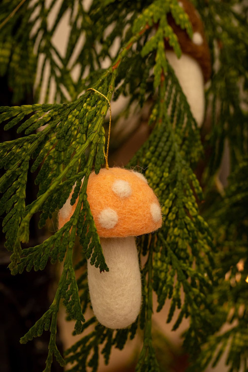 Christmas ornament in the shape of a small felt mushroom hanging from the tree