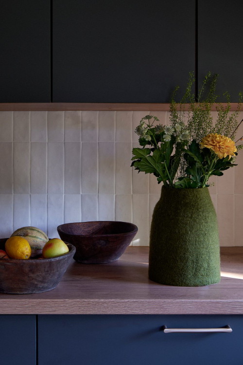 Green wool felt vase with a bouquet on a kitchen counter