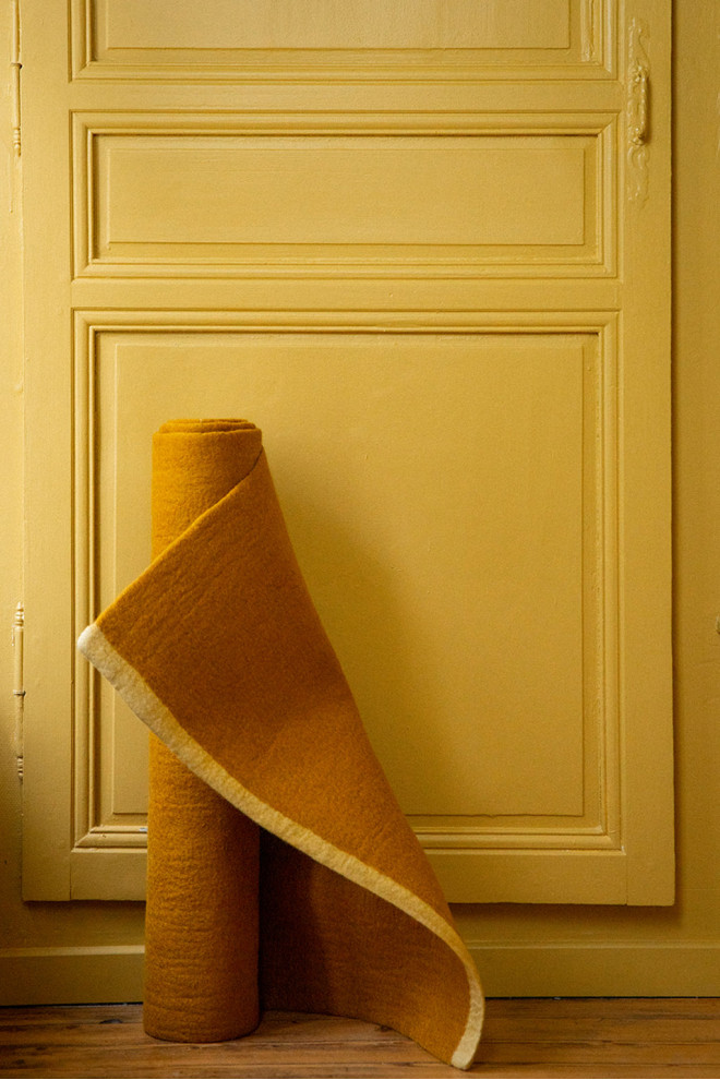 Ochre rectangle wool felt carpet rolled in front of a door