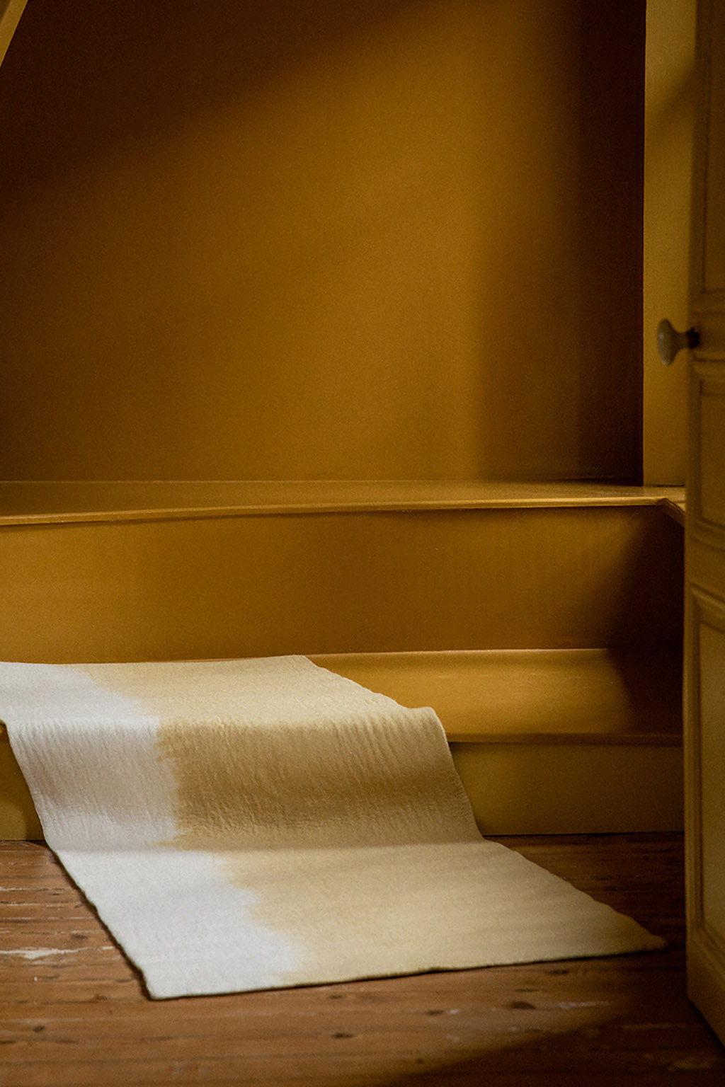 Long rectangular yellow and white felt carpet on yellow stairs