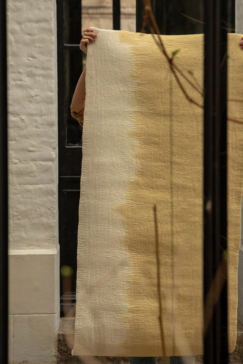 Rectangular carpet in yellow and white felt worn by a woman