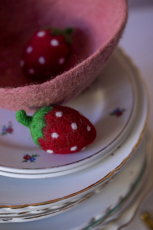 une fraise en feutre décore une assiette en porcelaine