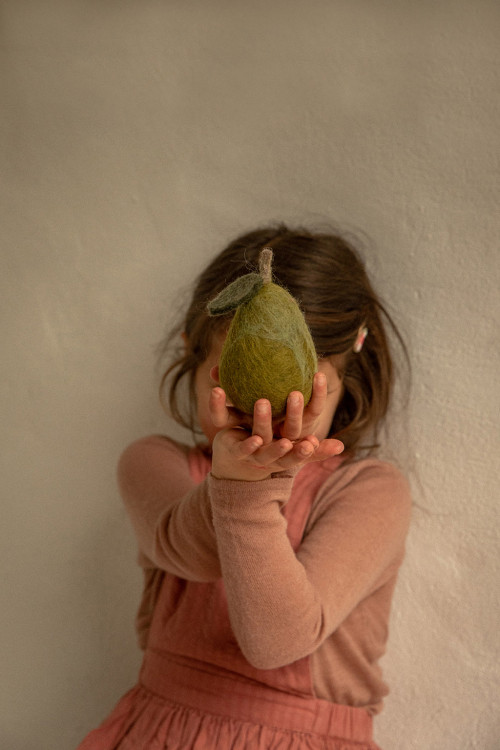 une enfant tient une poire en laine moelleuse et douce