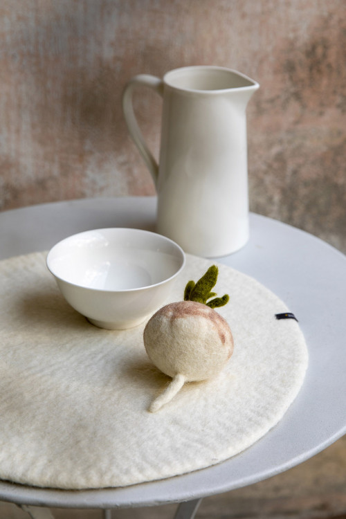 a felt turnip placed on a woolen placemat creates a natural decoration
