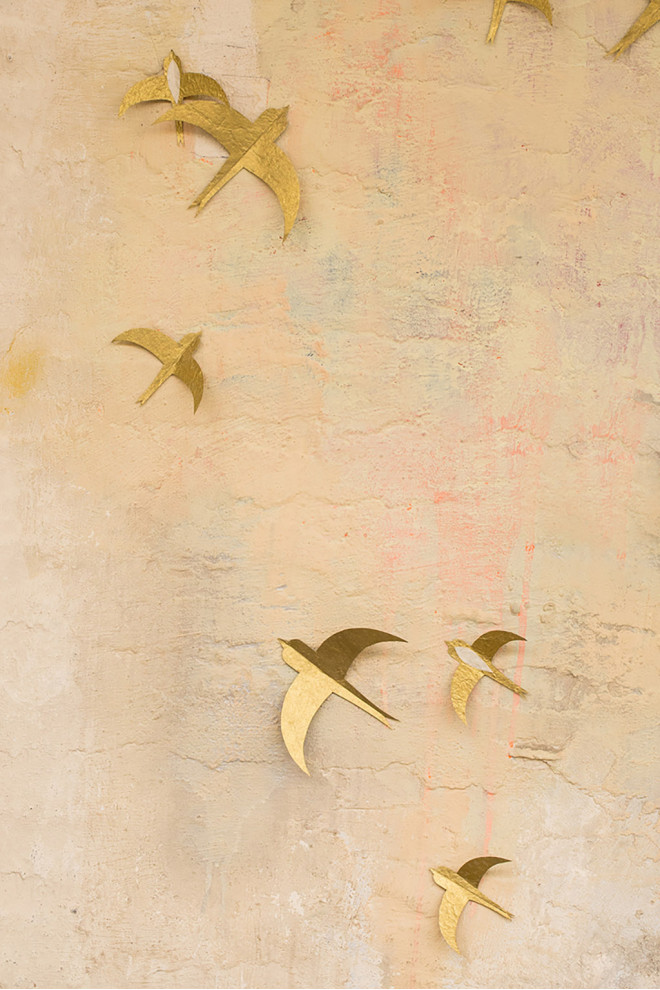 an ochre wall decorated with 2 black swallows in lokta paper