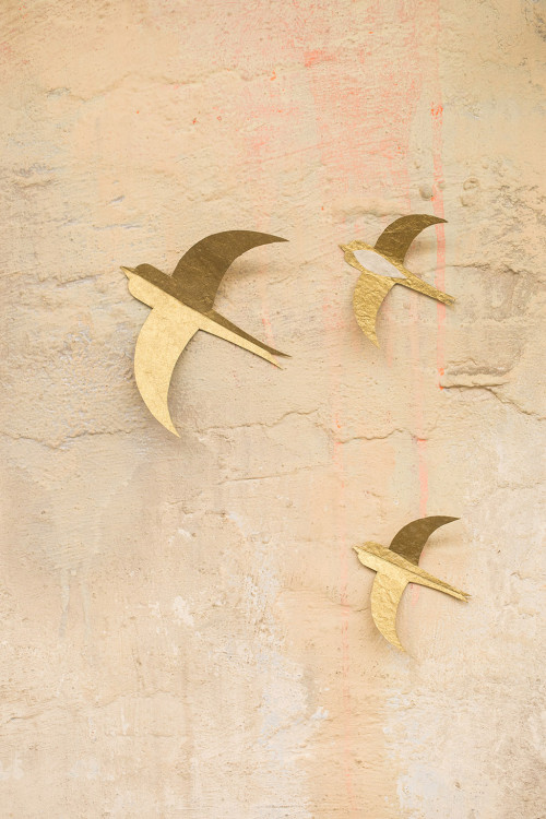trois hirondelles fabriquées artisanalement en papier lokta décorent un mur