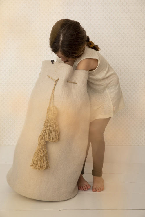 a child looks for her toys in a large beige felt basket a child looks for her toys in a large beige felt basket
