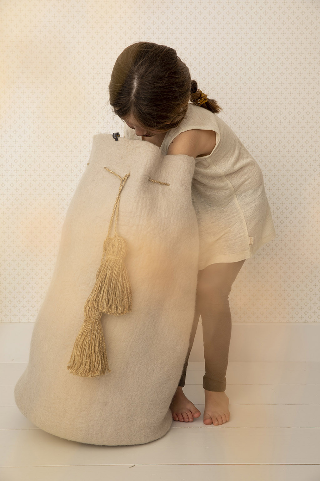 a child looks for her toys in a large beige felt basket
