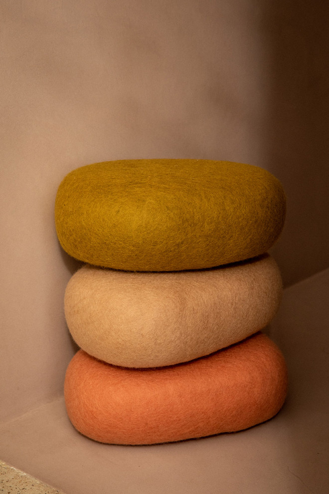 Oval felt cushions stacked along a wall