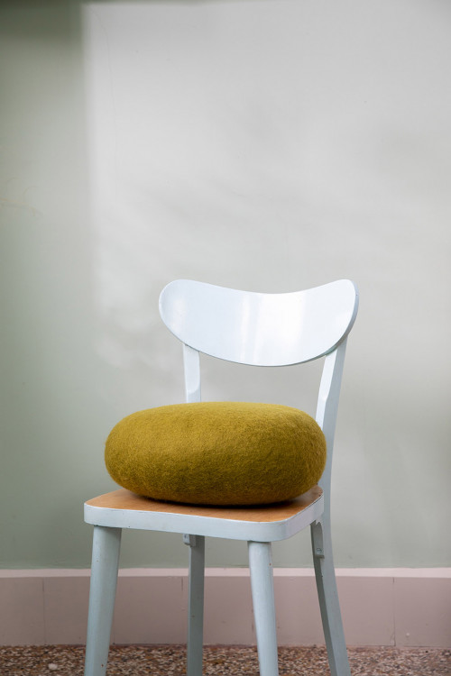 Thick oval cushion in felted wool on a chair