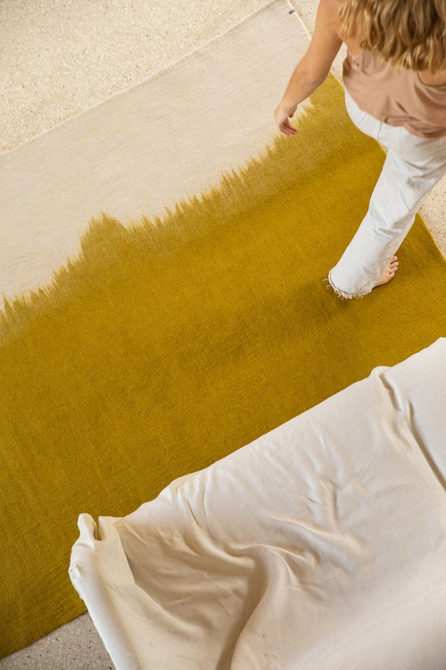 Woman walking on a large rectangle carpet in grey and green felt Woman walking on a large rectangle carpet in grey and green felt