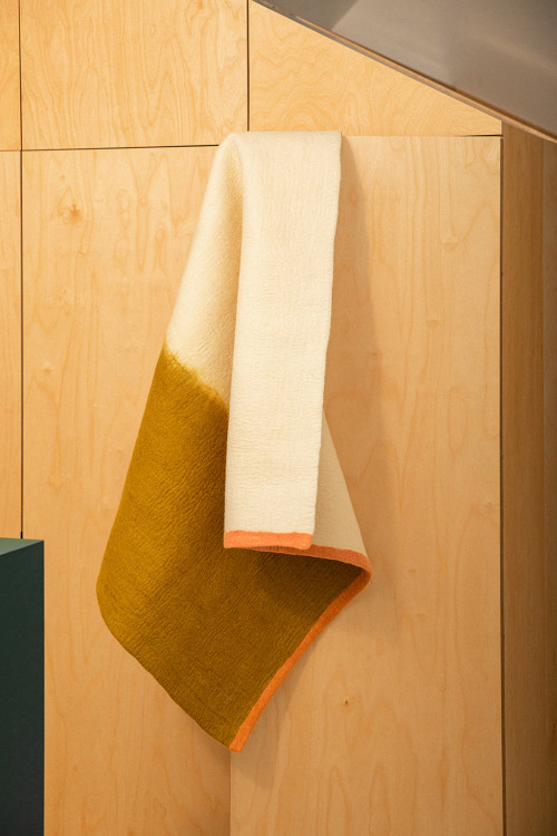 Rectangular white green and pink wool felt carpet hanging from a door