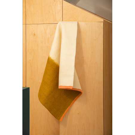 Rectangular white green and pink wool felt carpet hanging from a door