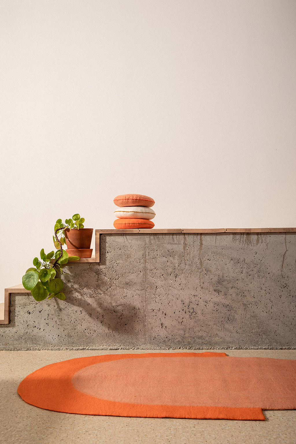 Pink and orange oval felt carpet and a stack of 3 small round felted wool cushions