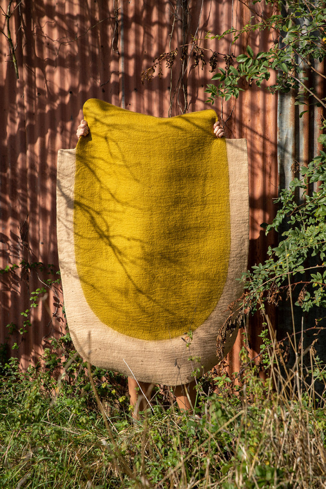 Two-tone oval wool felt carpet in yellow and ochre for a modern decoration