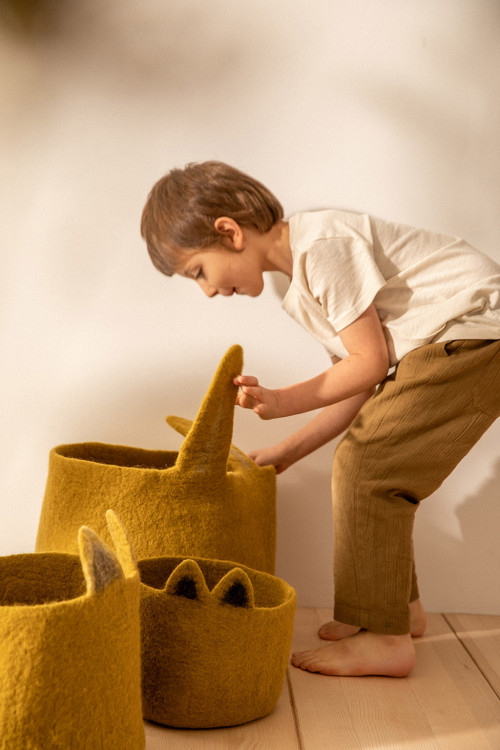 un enfant range ses jouets dans un panier de rangement en forme de lapin un enfant range ses jouets dans un panier de rangement en forme de lapin