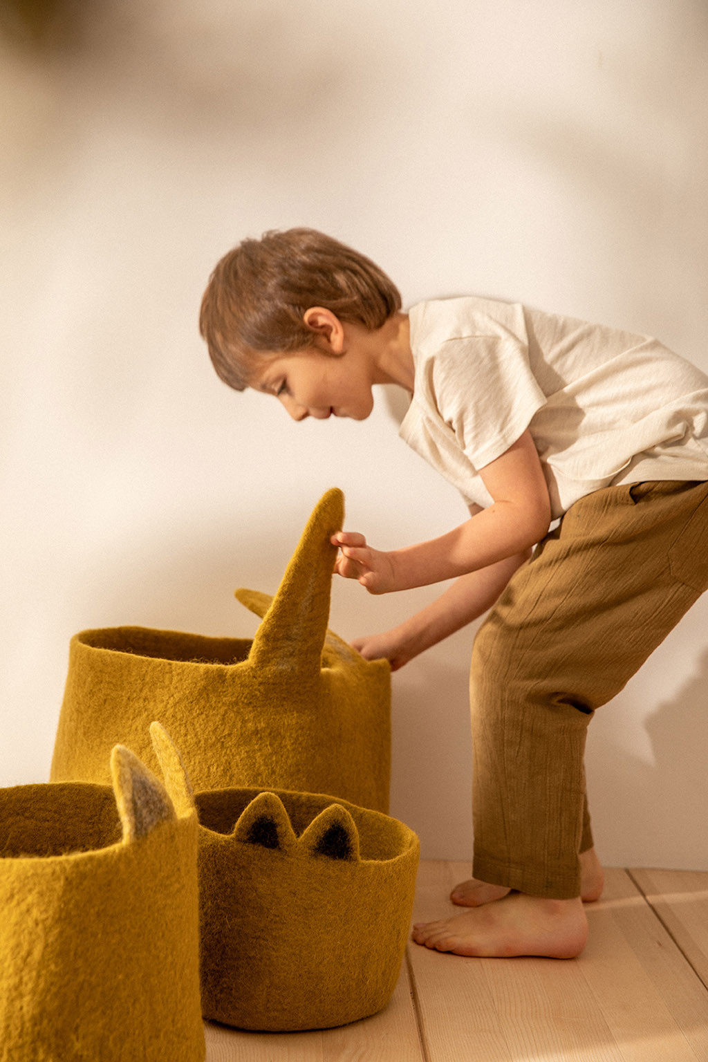 un enfant range ses jouets dans un panier de rangement en forme de lapin