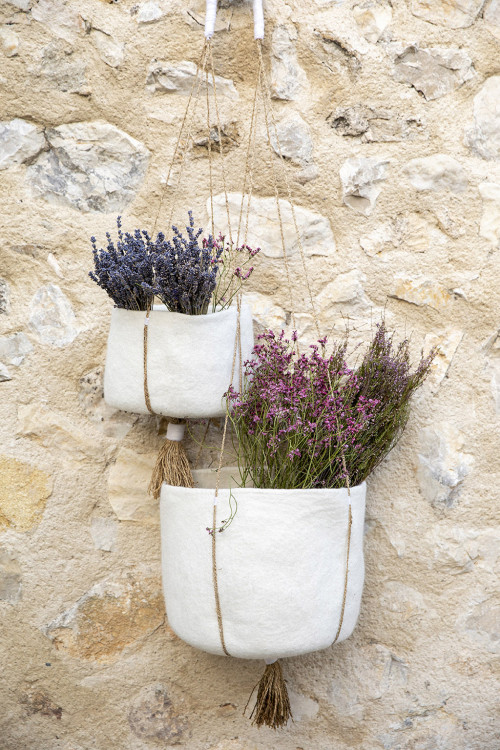 2 felt pot covers hanging on the wall of a stone house