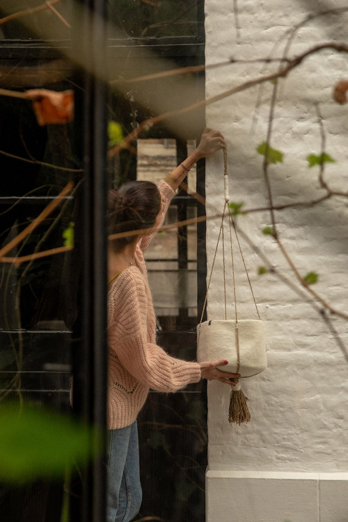 a felt basket is hung on the wall with hemp ties