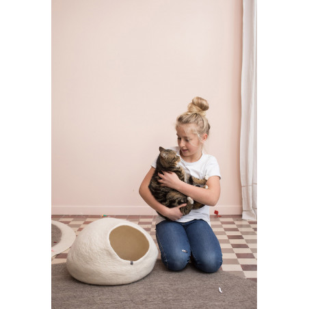 une fille caresse le chat à côté de son panier à chat en laine bouillie