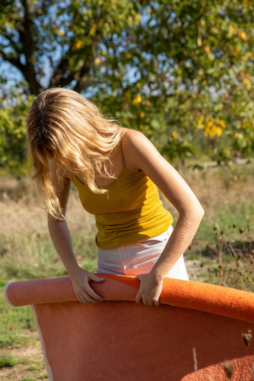 Woman rolling an orange felted wool rug