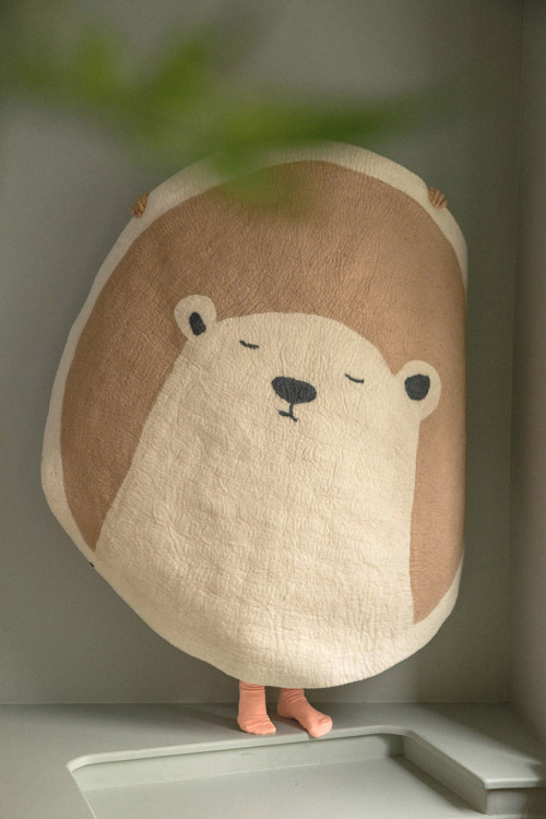 Little girl carrying a white and pink wool felt bear rug
