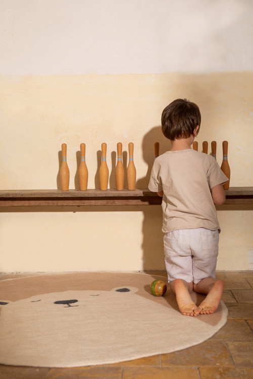 Petit garçon jouant sur un tapis rond imprimé ours rose et blanc et laine feutrée
