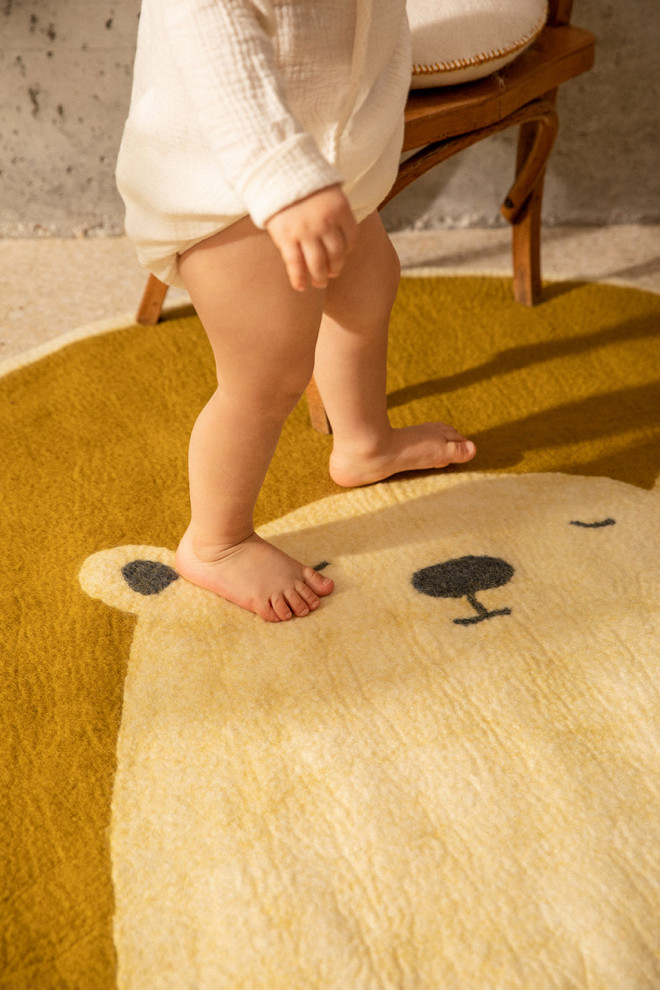 Little girl carrying a white and pink wool felt bear rug