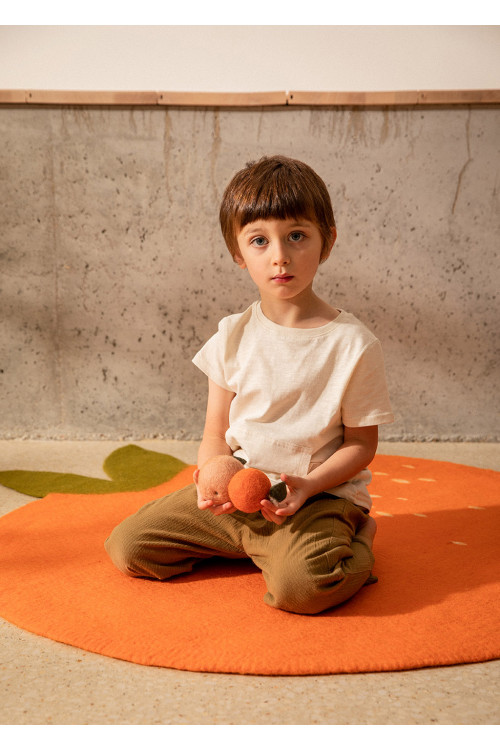 Petit garçon sur un tapis clémentine orange en feutre de laine pour enfant