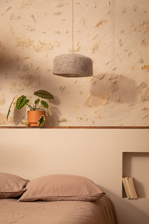 Small hanging light made of natural felt above the bed