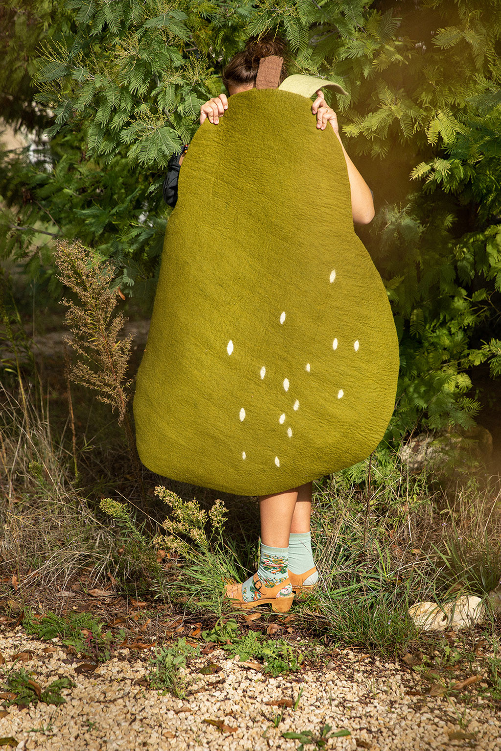 Felt green carpet for child in the shape of a pear carried by a woman