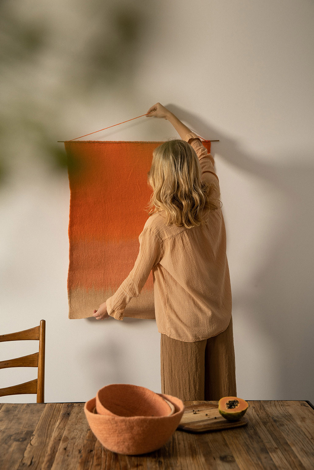 Woman hanging a tri-colored felt and bamboo decoration on the wall