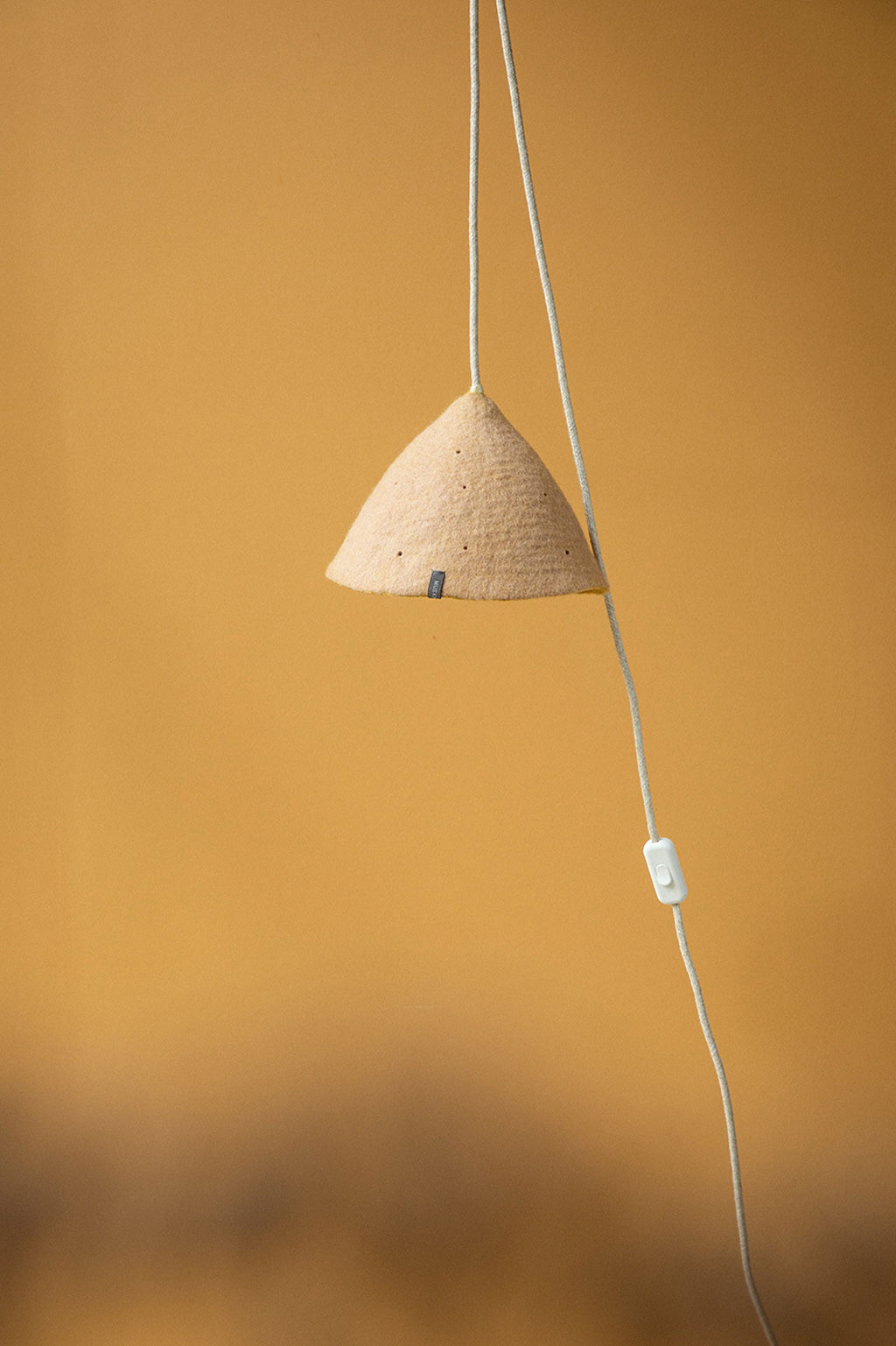 Ochre wall and felt light suspension for a warm decoration