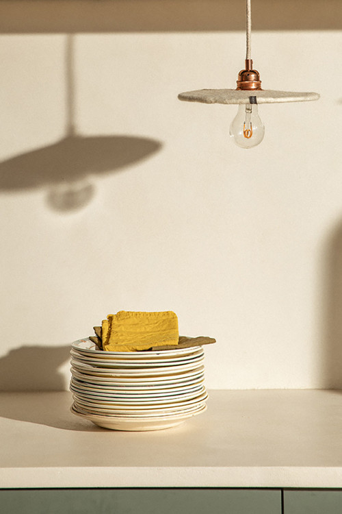 A flat hanging light made of wool felt above the worktop in the kitchen