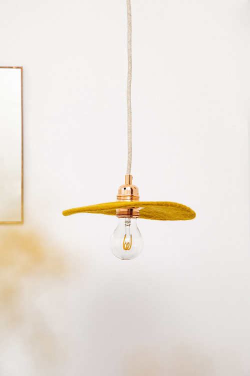 Gold coloured hanging light in felt and copper details for a decoration in the air of time