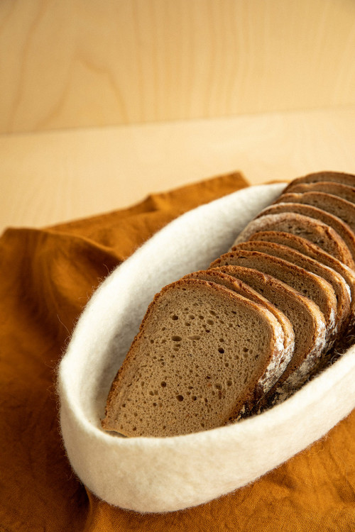 An oval bread basket in beige felted wool for the table