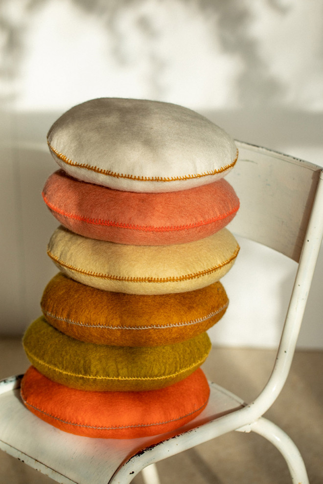 Stack of four felted cushions on a stool