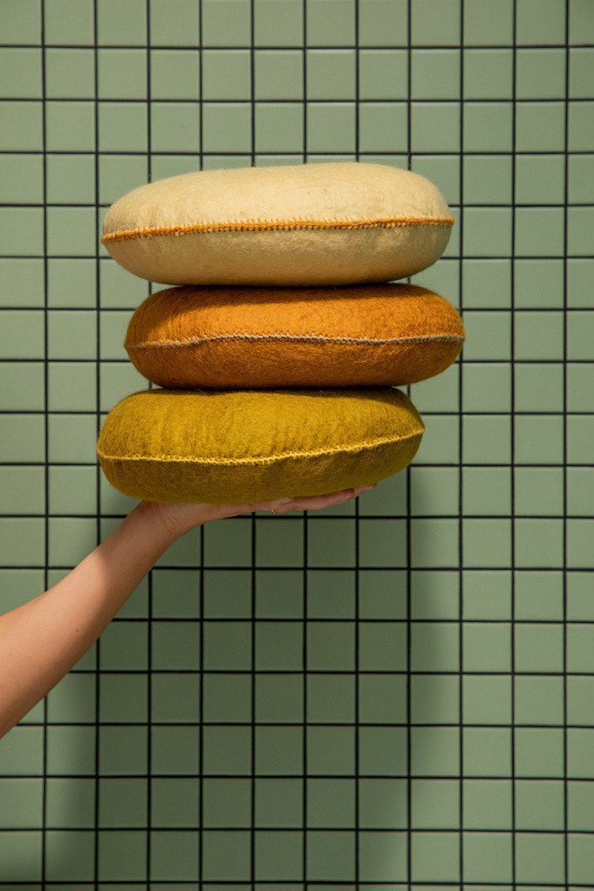 Stack of four felted cushions on a stool