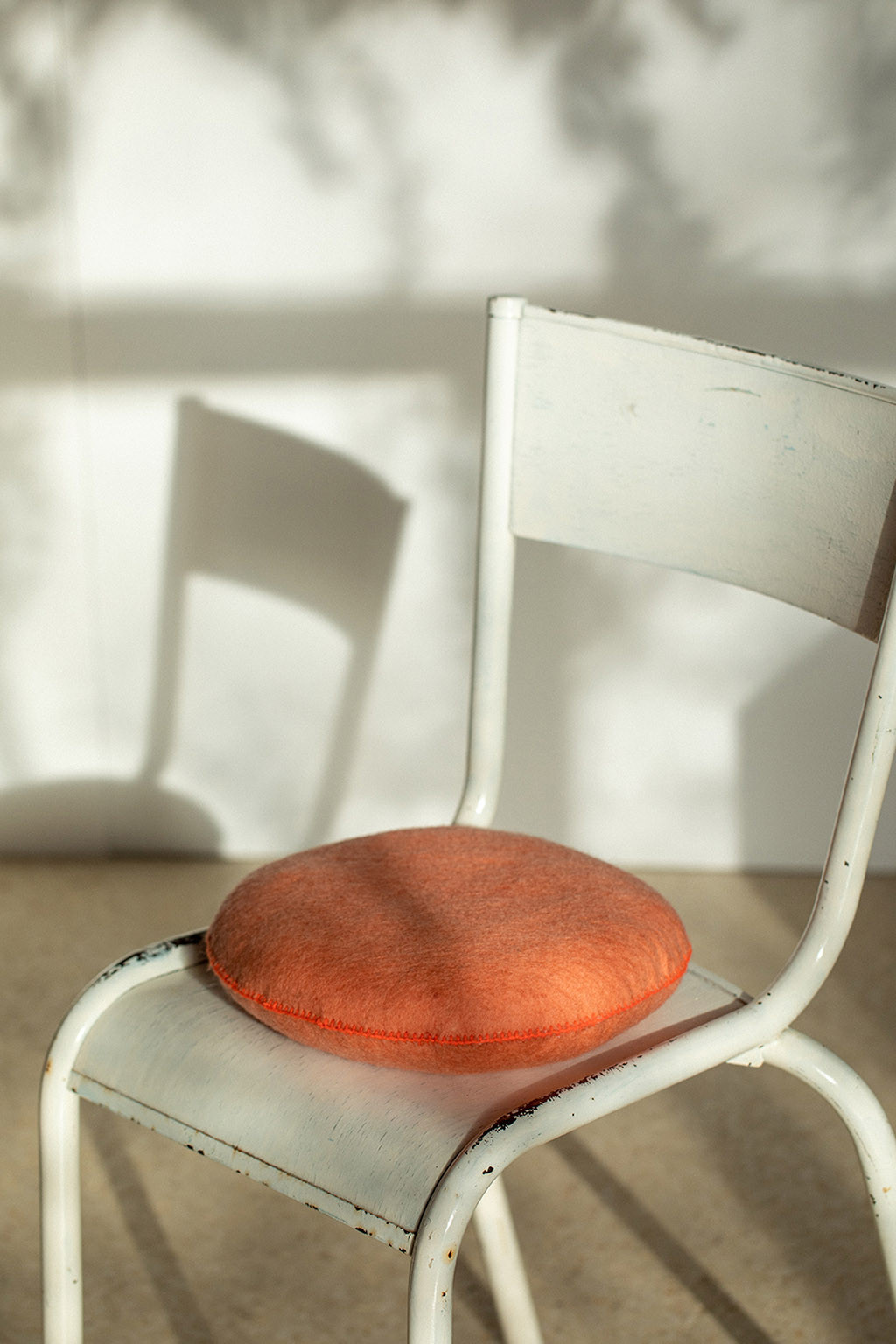Round litchee cushion in felt on a white chair