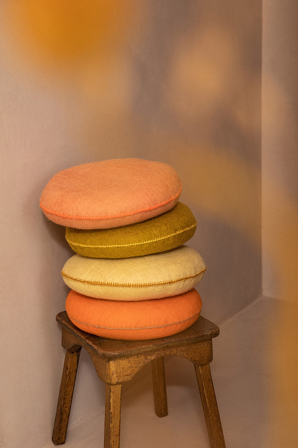 Pile de quarte coussins feutrés sur un tabouret