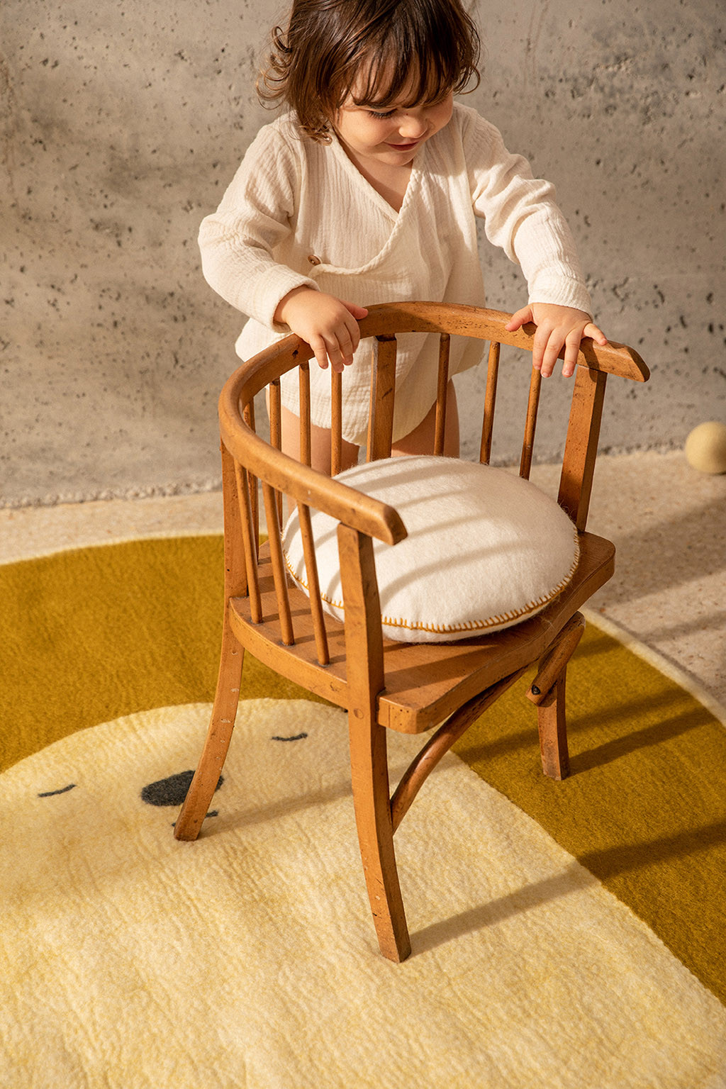 Ambiance joyeuse dans une chambre d'enfant avec un coussin en feutre blanc et un tapis en laine bouillie