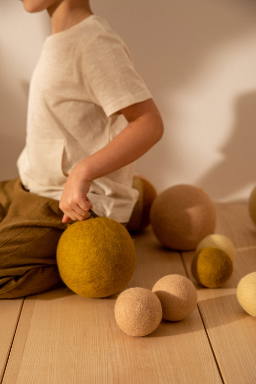 un enfant joue avec ses balles en feutre colorées